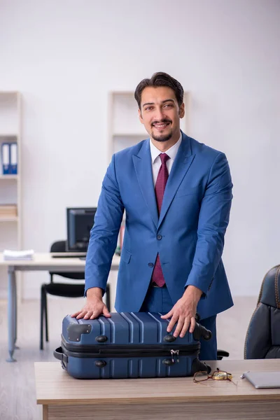 Joven empleado masculino preparándose para el viaje en el lugar de trabajo —  Fotos de Stock