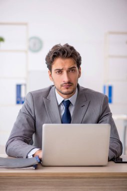 Genç erkek çalışan işyerinde oturuyor.