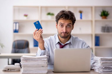 Genç bir erkek çalışan ve ofiste çok fazla iş var.