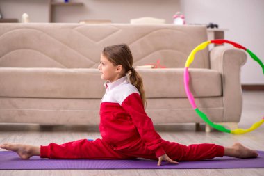 Küçük kız evde spor yapıyor.