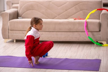 Küçük kız evde spor yapıyor.