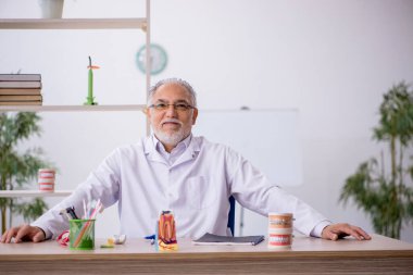 Klinikte çalışan yaşlı erkek dişçi.