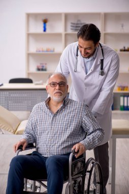 Tekerlekli sandalyedeki yaşlı adam genç erkek doktoru ziyaret ediyor.