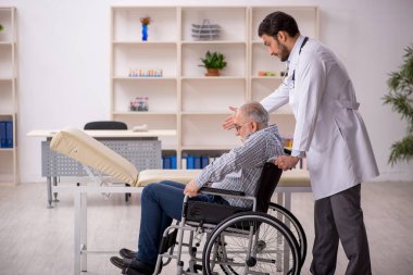 Tekerlekli sandalyedeki yaşlı adam genç erkek doktoru ziyaret ediyor.
