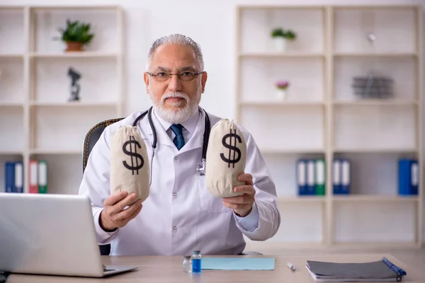 Viejo doctor en concepto de remuneración —  Fotos de Stock