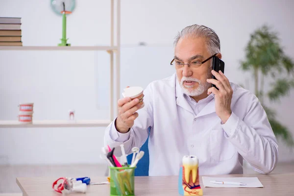 Starý zubař pracující na klinice — Stock fotografie