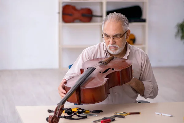 Starý opravář mužského pohlaví opravuje hudební nástroje v dílně — Stock fotografie
