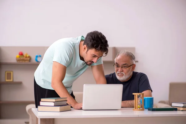 Grootvader en kleinzoon thuis met computer — Stockfoto