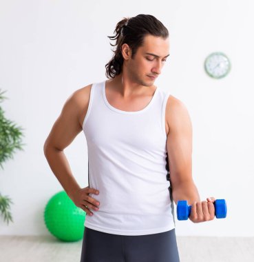 Genç yakışıklı adam içeride spor yapıyor.