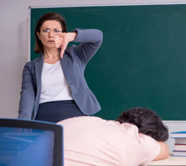 Old female teacher and male student in the classroom — Stock Photo, Image