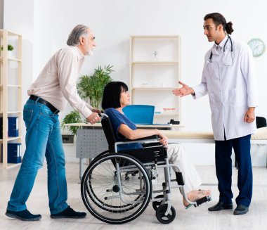 Yaşlı çift genç erkek doktoru ziyaret ediyor.