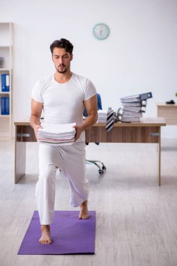 Genç erkek çalışan ofiste spor egzersizleri yapıyor.