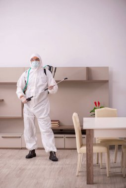 Genç erkek müteahhit evde haşere kontrolü yapıyor.