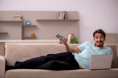 Genç adam evde televizyon izliyor.