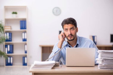 Genç bir erkek çalışan ve ofiste çok fazla iş var.