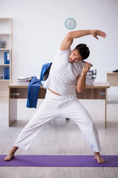 Mladý muž zaměstnanec dělá sportovní cvičení v kanceláři — Stock fotografie