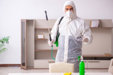 Genç erkek müteahhit evde haşere kontrolü yapıyor.