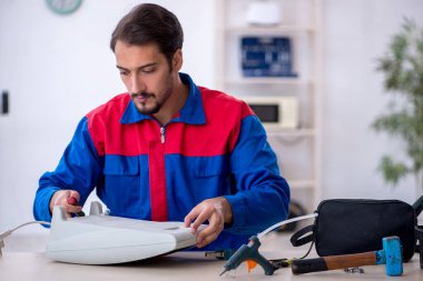 Genç erkek tamirci ısıtıcıyı tamir ediyor.