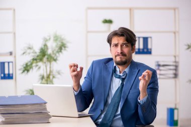 Genç bir erkek çalışan ve ofiste çok fazla iş var.