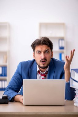 Genç bir erkek çalışan ve ofiste çok fazla iş var.