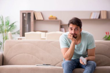 Evde televizyon izleyen genç bir öğrenci.