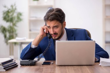 Ofisteki aşırı işten memnun olmayan genç bir erkek işçi.