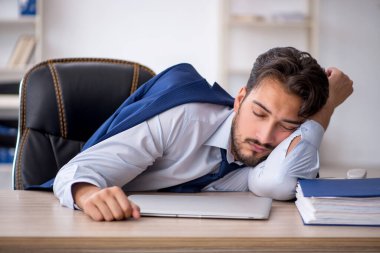 Genç erkek çalışan ofiste çok yorgun.