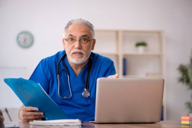 Klinikte çalışan yaşlı erkek doktor.