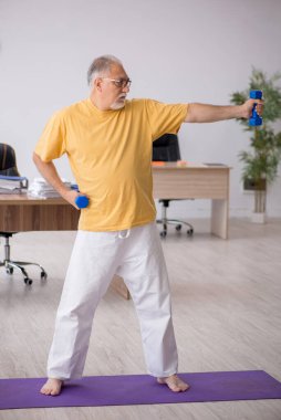 Ofiste spor egzersizleri yapan eski bir işadamı.