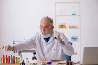 Uyuşturucu sentezi konseptinde yaşlı bir erkek kimyager.