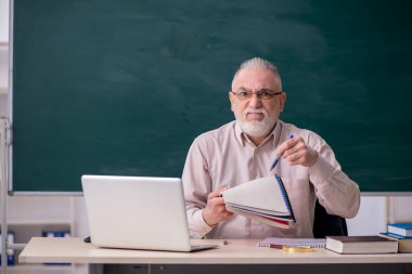Tahtanın önünde yaşlı bir erkek öğretmen.