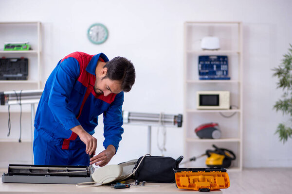 Young male repairman repairing air-conditioner