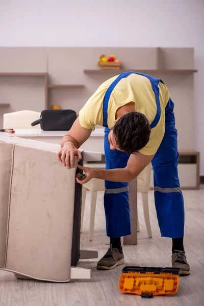 Jovem carpinteiro masculino reparando cadeira de braço em casa — Fotografia de Stock