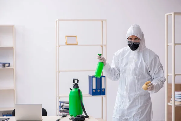 Young male contractor disinfecting office during pandemic — Stock Photo, Image
