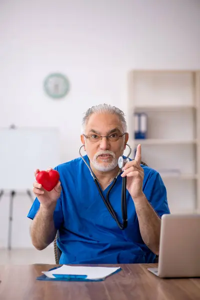 Viejo médico cardiólogo que trabaja en la clínica — Foto de Stock
