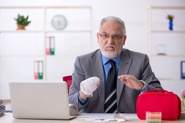 Alter männlicher Mitarbeiter schneidet sich im Büro die Hand ab — Stockfoto