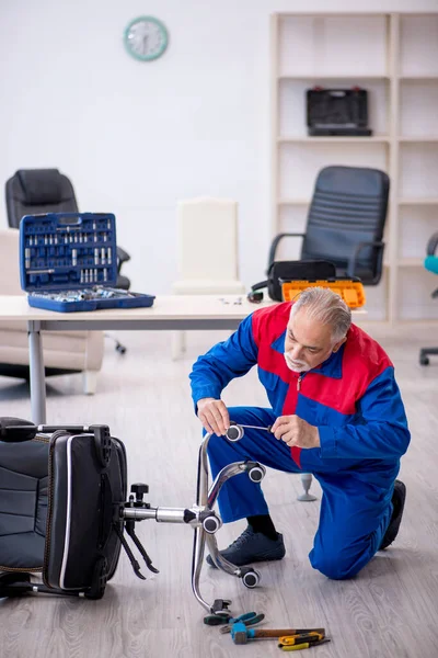 Vieux réparateur masculin réparation chaise de bureau — Photo