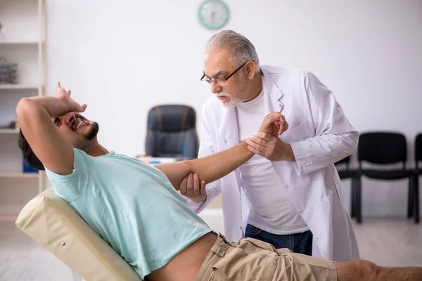 Genç erkek hasta yaşlı erkek doktoru ziyaret ediyor. — Stok fotoğraf