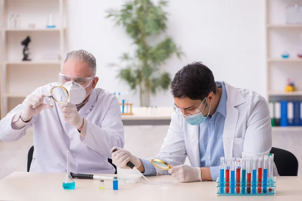 Két férfi vegyész dolgozik a laborban a világjárvány idején. — Stock Fotó