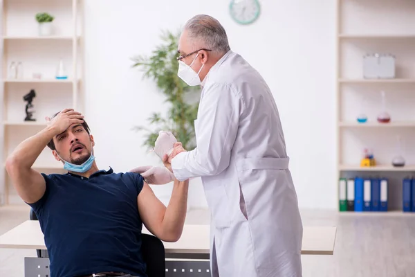 Junge männliche Patientin besucht alten Arzt im Impfpass — Stockfoto