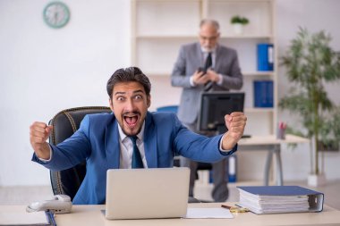 Yaşlı erkek patron ve ofiste çalışan genç erkek çalışan.