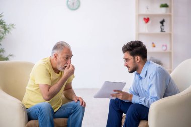 Yaşlı adam genç erkek psikoterapisti ziyaret ediyor.