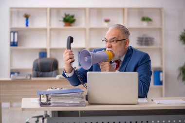 Ofiste megafon tutan kızgın yaşlı bir işadamı.