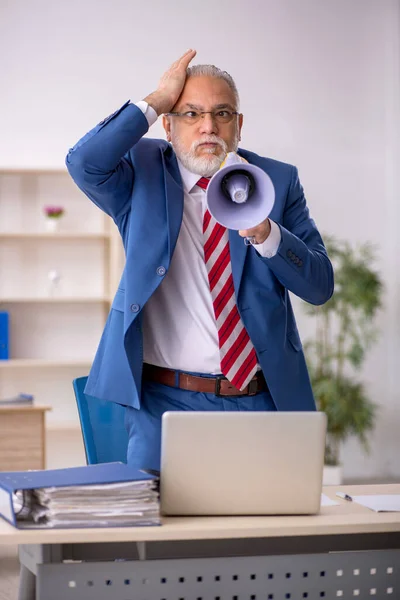 Vecchio uomo d'affari arrabbiato che tiene il megafono in ufficio — Foto Stock
