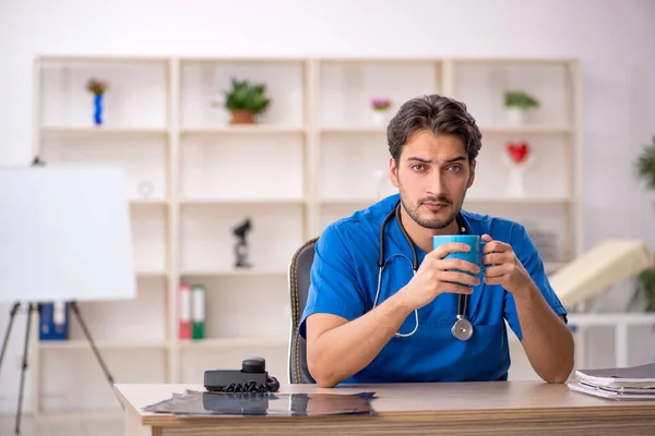 Ung manlig läkare dricker kaffe under rasten — Stockfoto