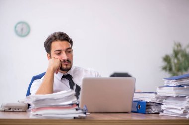 Genç bir erkek çalışan ve ofiste çok fazla iş var.