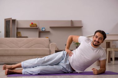 Genç adam evde spor yapıyor.