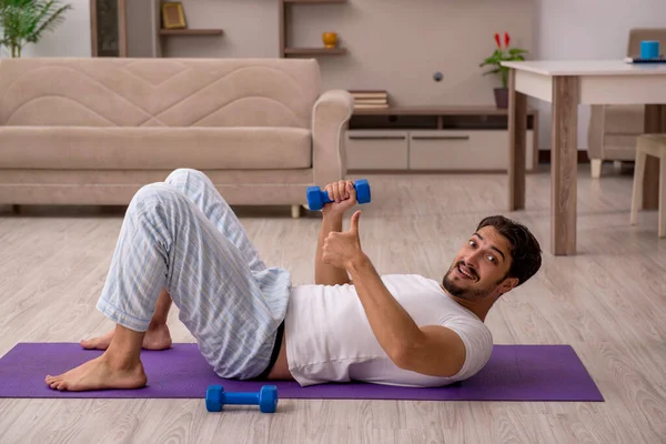 Jovem fazendo exercícios esportivos em casa — Fotografia de Stock