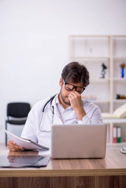 Klinikte çalışan genç erkek doktor.