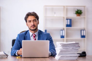 Genç bir erkek çalışan ve ofiste çok fazla iş var.